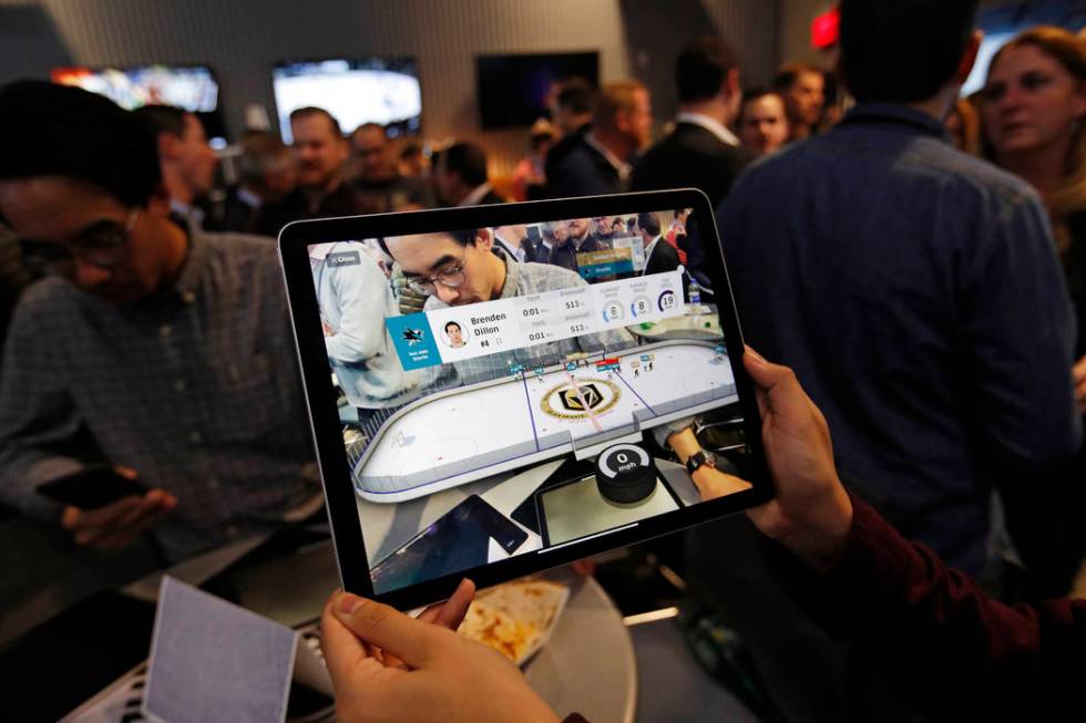 People watch real-time puck and player tracking technology on display during an NHL hockey game ...