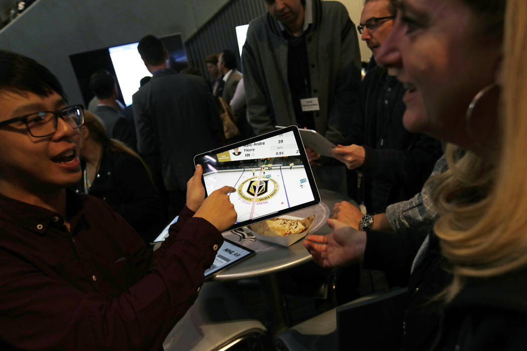 People watch real-time puck and player tracking technology on a tablet during an NHL hockey gam ...