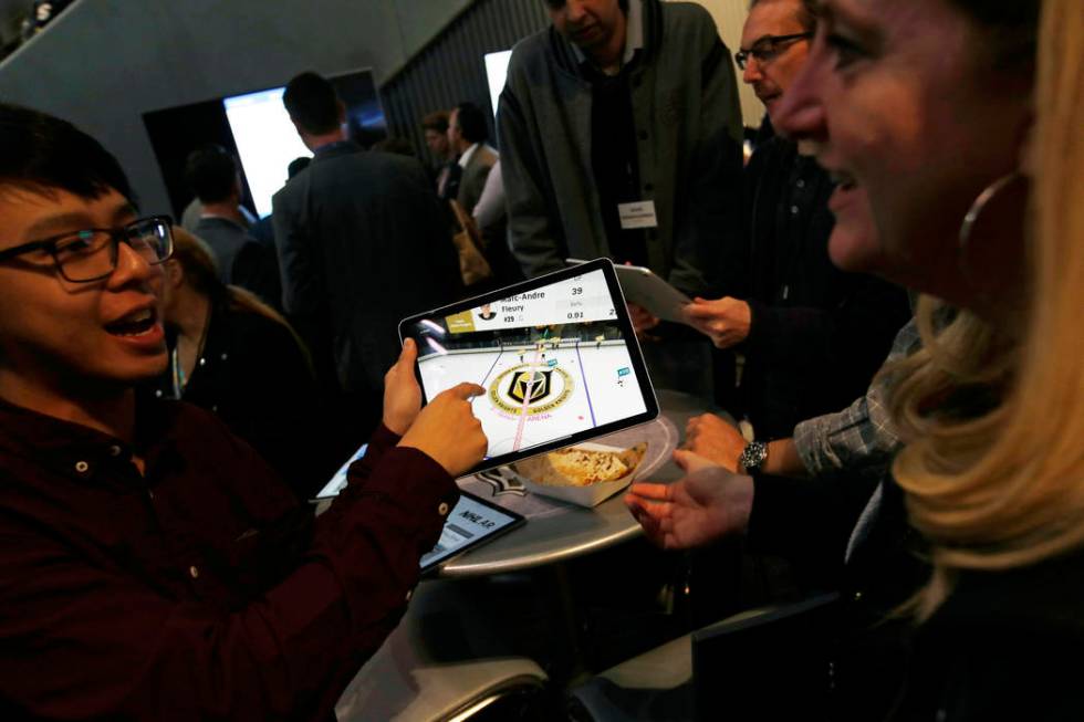 People watch real-time puck and player tracking technology on a tablet during an NHL hockey gam ...