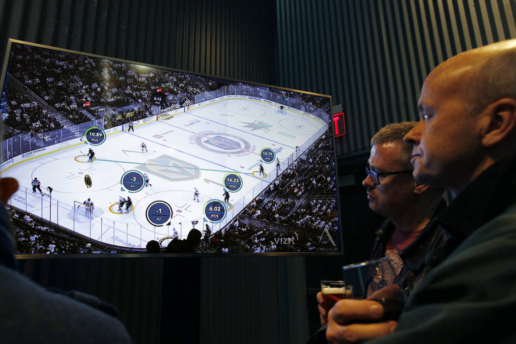 People watch real-time puck and player tracking technology on display during an NHL hockey game ...