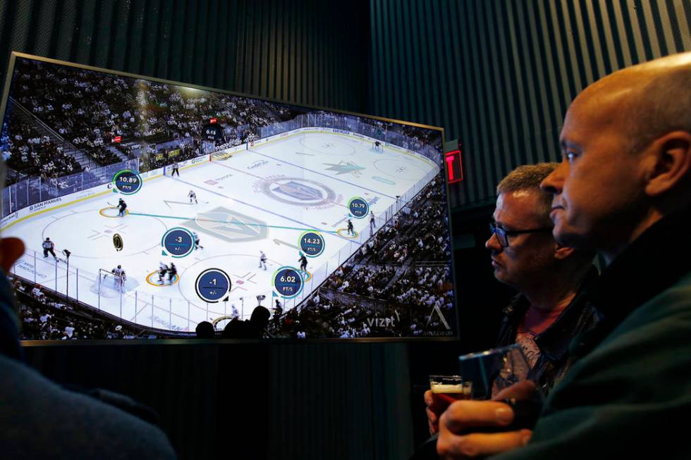 People watch real-time puck and player tracking technology on display during an NHL hockey game ...