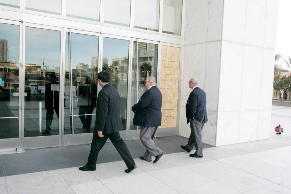 Three men approach the Lloyd George U.S. Courthouse past a wood panel replacing a window that w ...