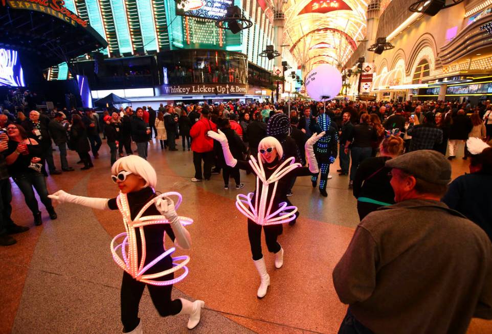 Costumed performers with the Champagne Creative Group walk through the crowd as New Year's Eve ...