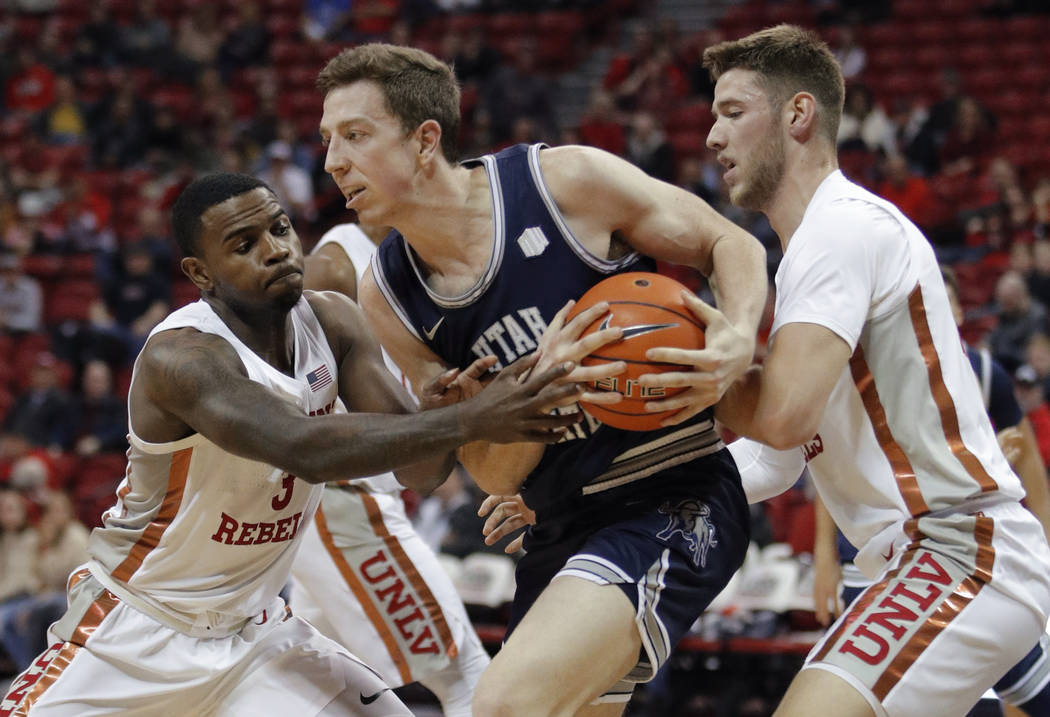 Utah State's Justin Bean, center, keeps the ball from UNLV's Amauri Hardy, left, and Vitaliy Sh ...