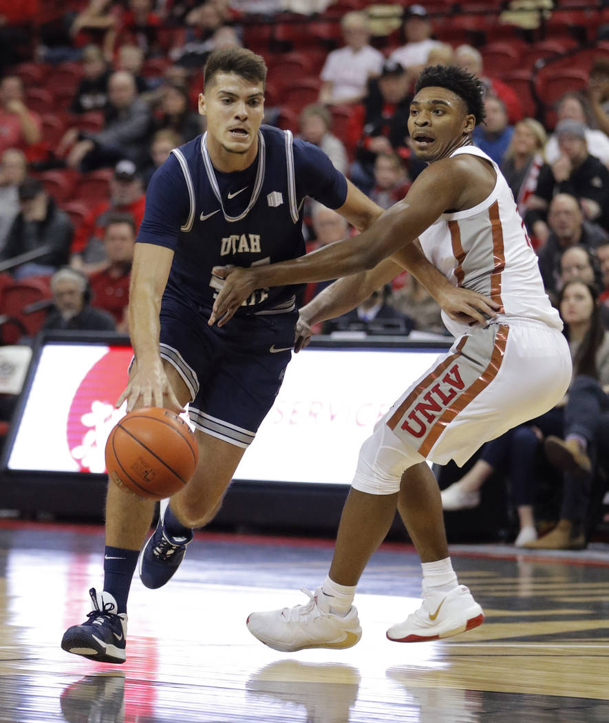 Utah State's Diogo Brito drives around UNLV's Bryce Hamilton during the first half of an NCAA c ...