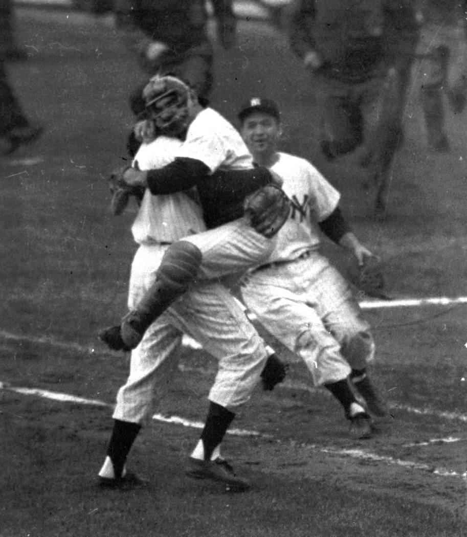 FILE- In this Oct. 8, 1956, file photo, New York Yankees catcher Yogi Berra is embraced by pitc ...