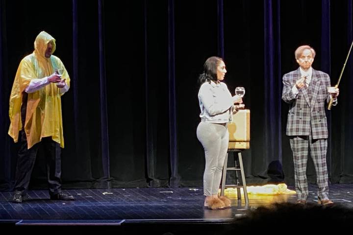 Penn Jillette, wearing the Cloak of Invisibility, and Mac King perform with an audience member ...