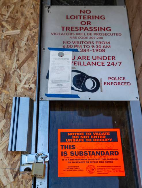 The front door is padlocked and marked with a dangerous building sign issued by the City of Las ...