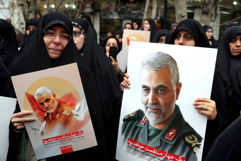 Protesters hold up posters of Gen. Qassem Soleimani while mourning during a demonstration over ...