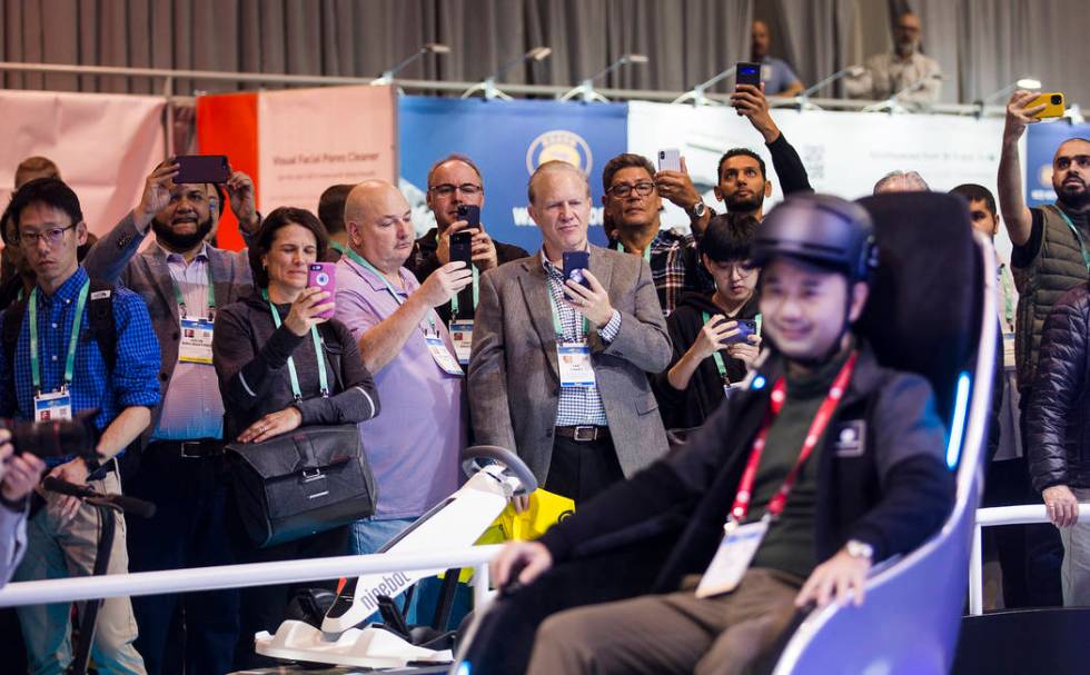 Attendees watch Segway Vice President Chen Huang demonstrate the S-Pod transporter at CES at th ...