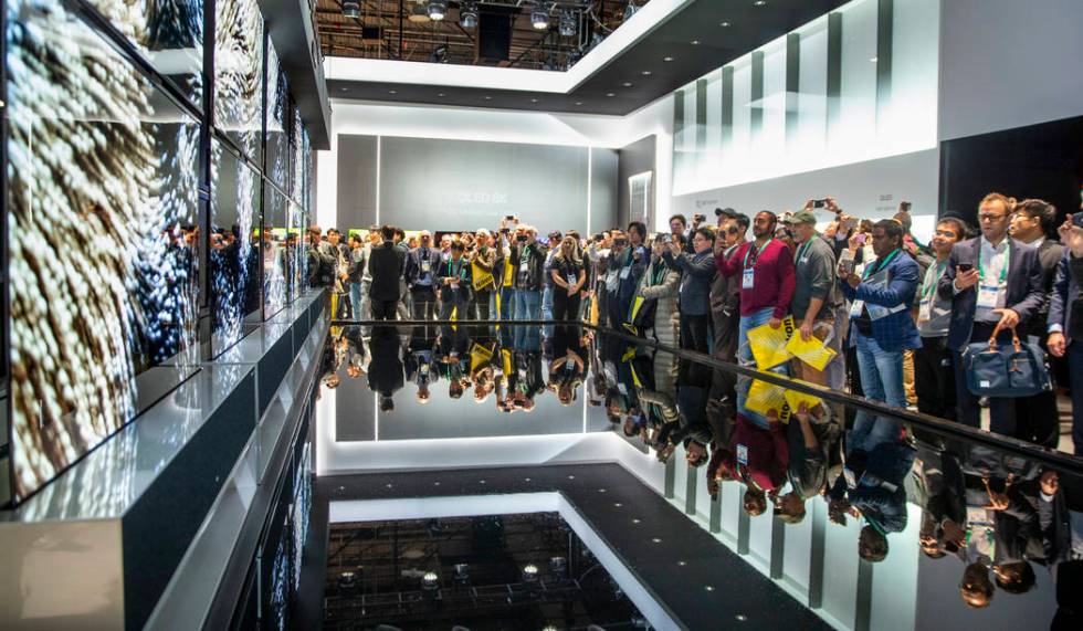 Attendees check out the new LG Signature OLED R televisions during CES Day 1 in Central Hall of ...