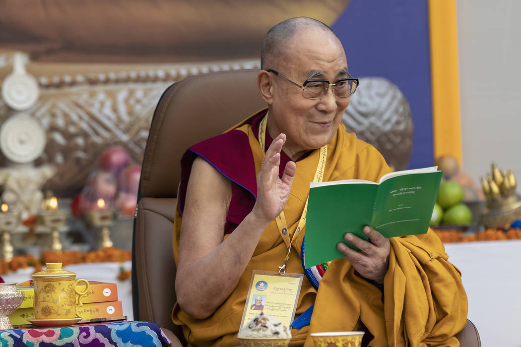 Tibetan spiritual leader the Dalai Lama smiles as he reads from a book during an event at the K ...