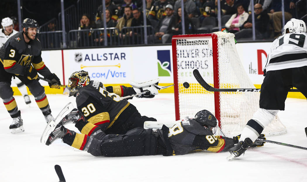 Los Angeles Kings' Alex Iafallo (19) sends the puck over Golden Knights' Nate Schmidt (88) and ...