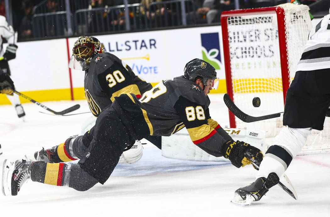 Los Angeles Kings' Alex Iafallo (19) sends the puck over Golden Knights' Nate Schmidt (88) and ...