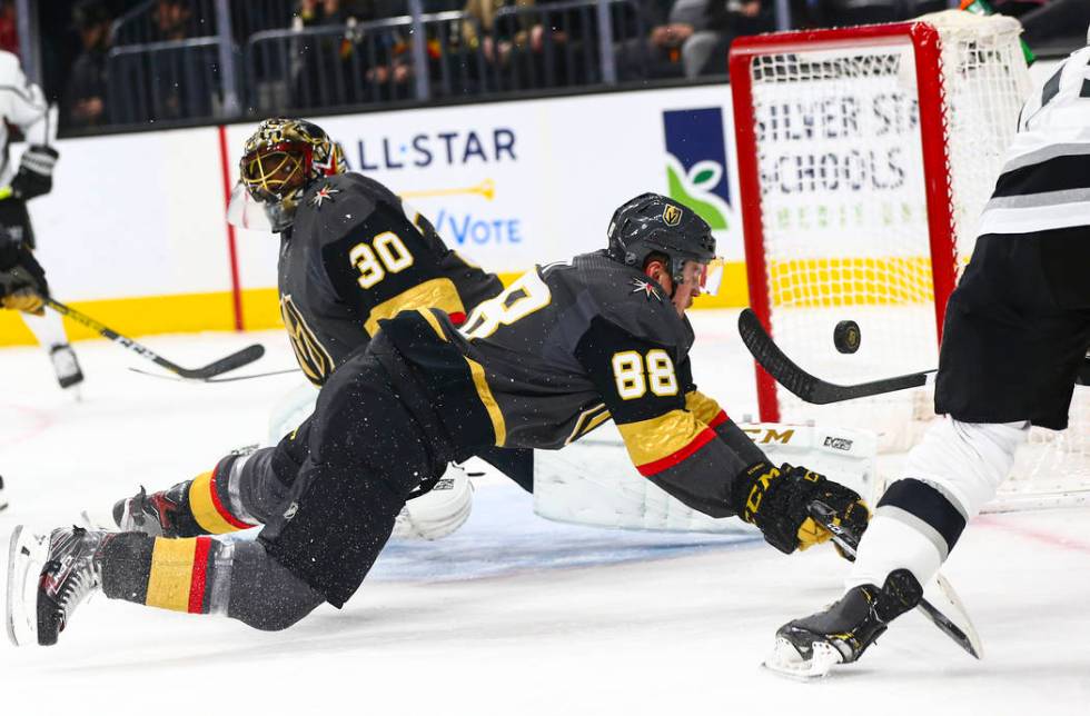 Los Angeles Kings' Alex Iafallo (19) sends the puck over Golden Knights' Nate Schmidt (88) and ...