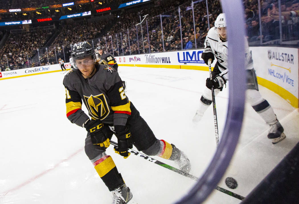 Golden Knights' Cody Eakin (21) moves the puck in front of Los Angeles Kings' Ben Hutton (15) d ...