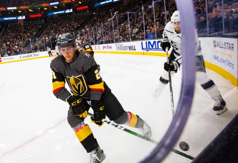 Golden Knights' Cody Eakin (21) moves the puck in front of Los Angeles Kings' Ben Hutton (15) d ...