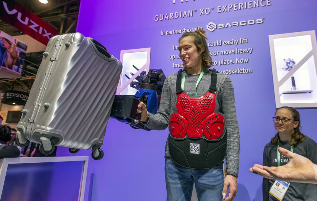Sam Landa lifts a 50 lb suitcase with the aid of a Sarcos Guardian XO Exoskeleton during CES Da ...