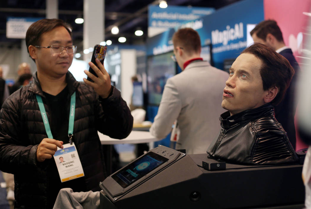 CES attendee Baoqing Wang of Shenzhen, China, photographs the animatronic bust of Arnold Schwar ...