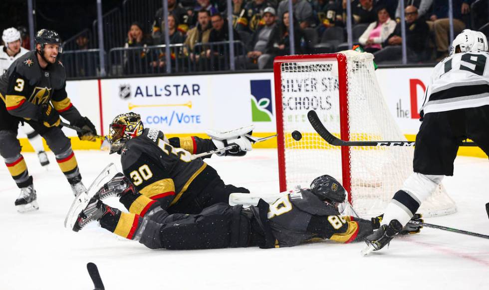 Los Angeles Kings' Alex Iafallo (19) sends the puck over Golden Knights' Nate Schmidt (88) and ...