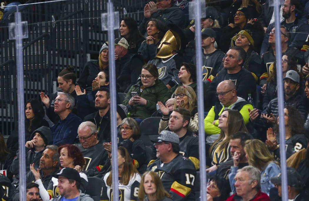 A Golden Knights fan wearing a mask watches the action during the first period of an NHL hockey ...