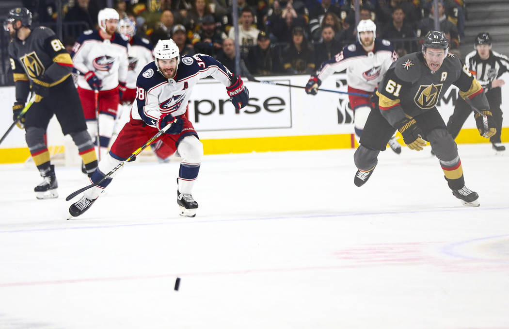 Columbus Blue Jackets' Boone Jenner (38) and Golden Knights' Mark Stone (61) chase after the pu ...