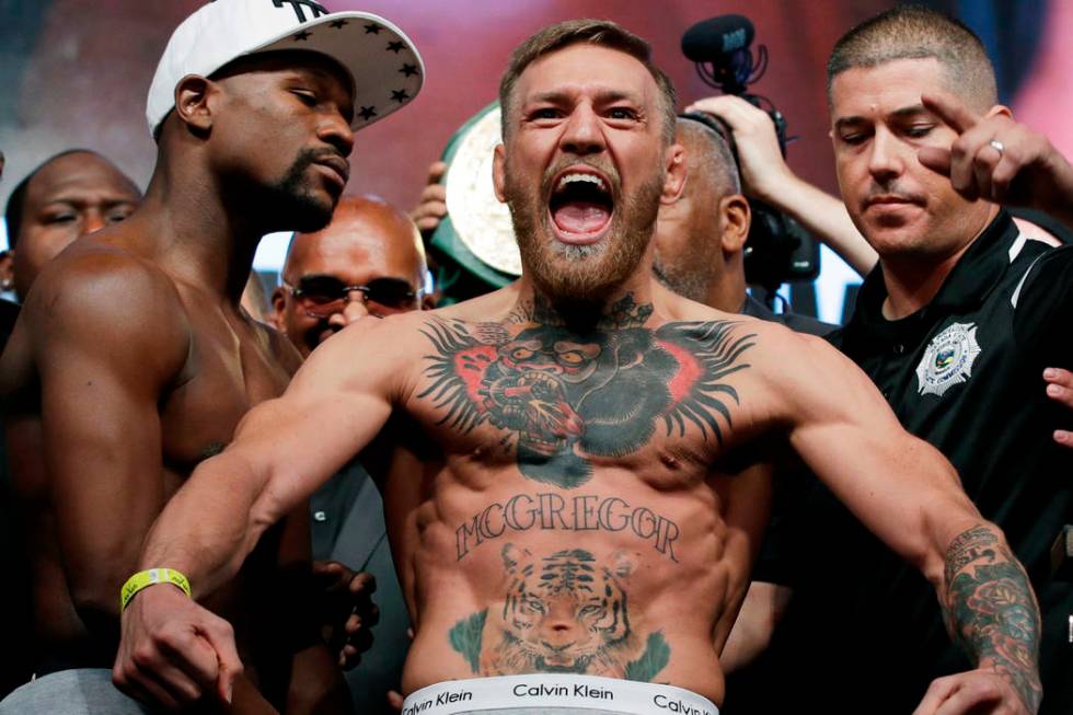 Conor McGregor, center, stands next to Floyd Mayweather Jr., center left, during their weigh-in ...