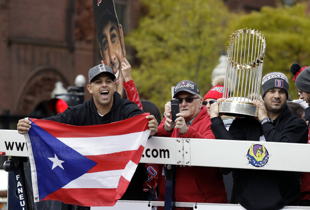 Boston Red Sox manager Alex Cora, left, waves the flag of Puerto Rico as coach Ramon Vazquez ho ...