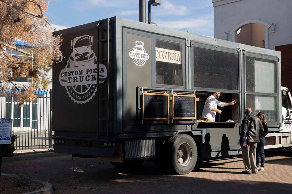 Chef Bartosz Wawrzyszak, owner of the Custom Pizza Truck, speaks with his costumers from his tr ...