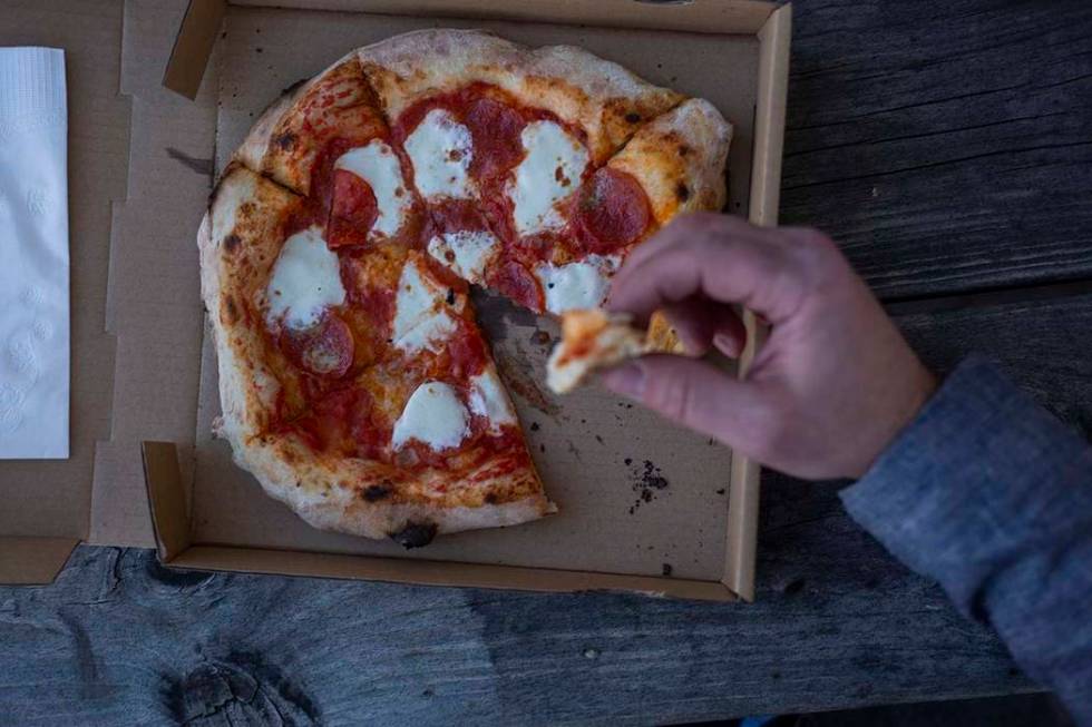 A Custom Pizza Truck costumer eats the Salami Gorgonzola pizza outside of the food truck on Thu ...