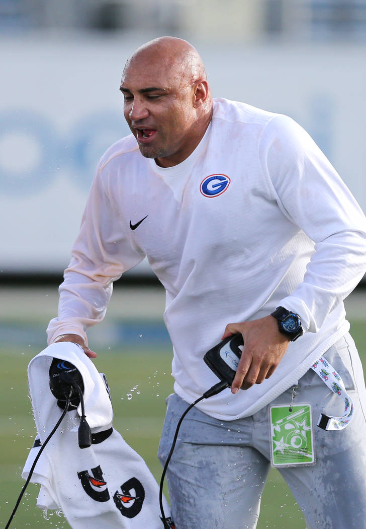 Bishop Gorman head coach Kenny Sanchez gets soaked by his players in the NIAA 4A state champion ...