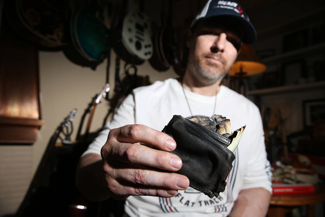 Scott Booth, a former pilot for Papillon Grand Canyon Helicopters, shows his charred wallet at ...