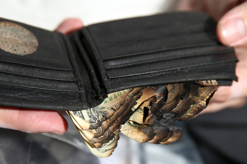 Scott Booth, a former pilot for Papillon Grand Canyon Helicopters, shows his charred wallet at ...