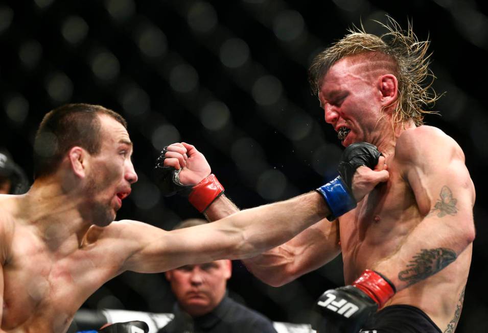 Tim Elliott, right, takes a hit from Askar Askarov during their flyweight bout at UFC 246 at T- ...