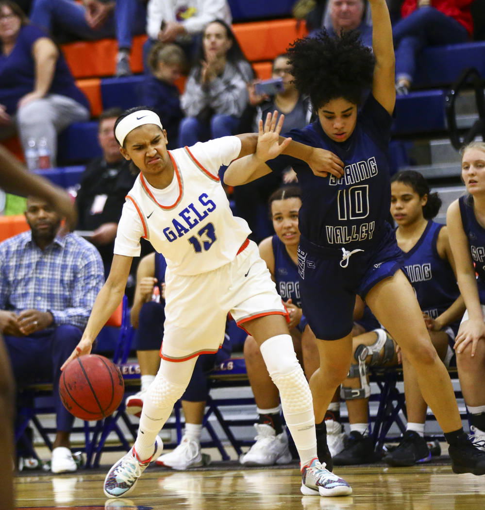 Bishop Gorman's Reina Bell (13) drives to the basket under pressure from Spring Valley's Riahan ...