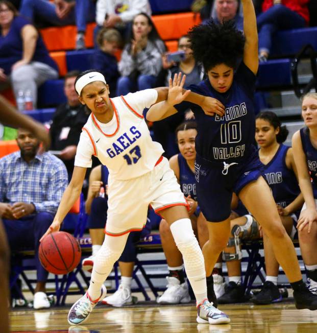 Bishop Gorman's Reina Bell (13) drives to the basket under pressure from Spring Valley's Riahan ...