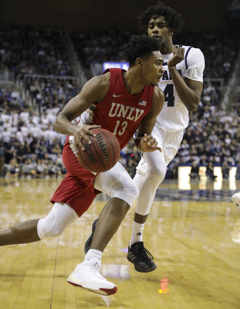 UNLV Rebels' Bryce Hamilton (13) drives to the basket against UNR's Lindsey Drew (14) during th ...