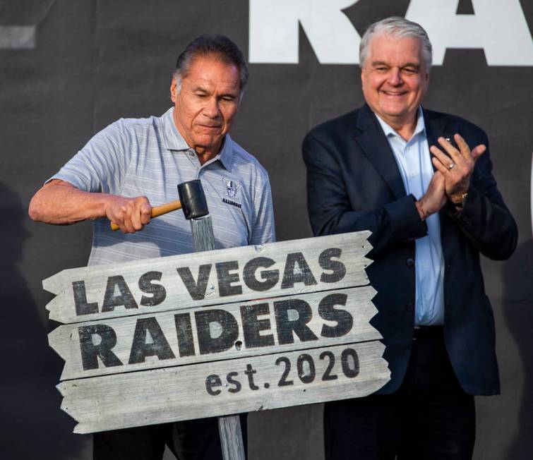 Former Oakland Raiders great Jim Plunkett, left, hammers a ceremonial sign into the ground besi ...