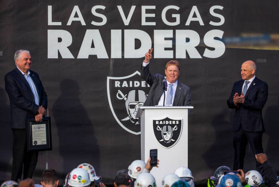 Nevada Gov. Steve Sisolak, left, looks to Raiders owner Mark Davis who addresses the crowd besi ...