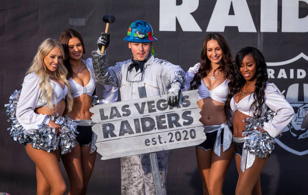 Painter Angel Ayala poses with a hammer between the Raiderettes during a special announcement a ...