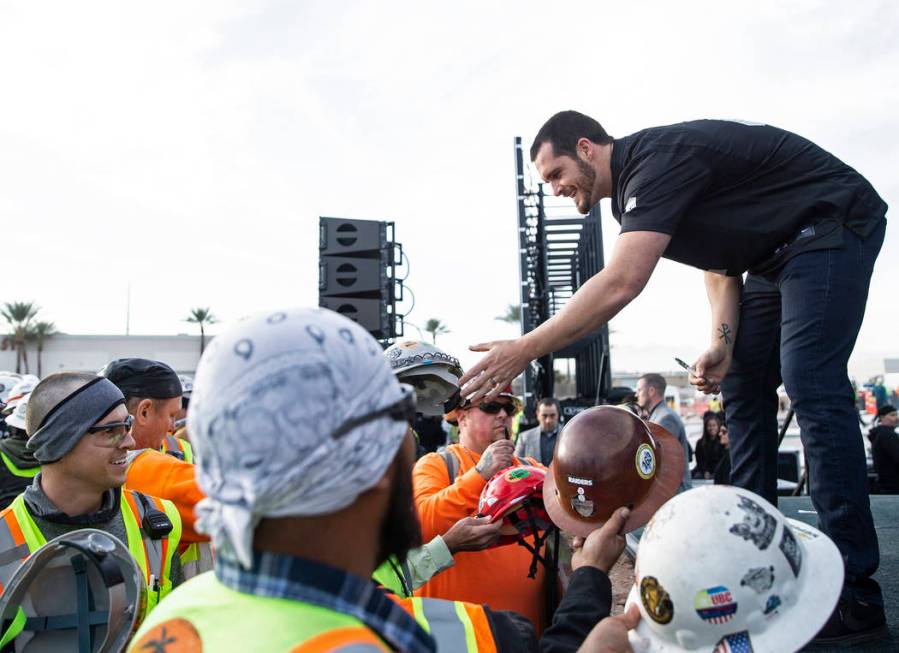 Raiders quarterback Derek Carr, right, signs autographs during a special announcement at the Al ...