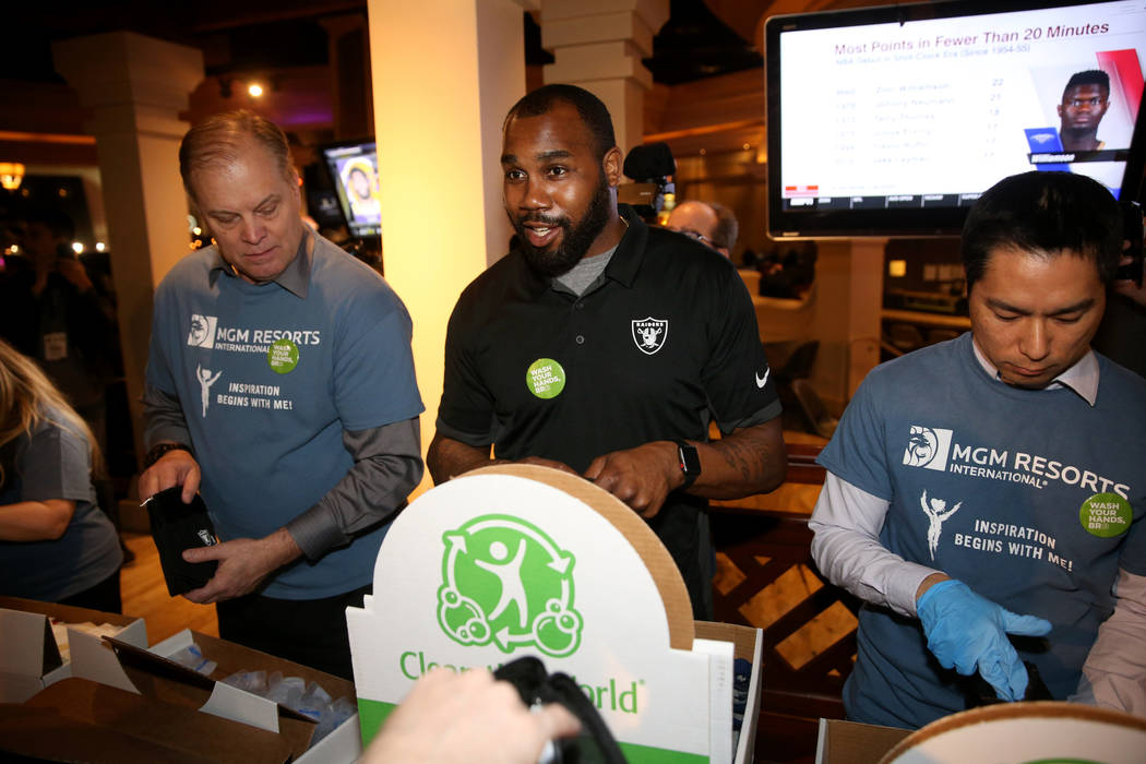 Raiders great Darren McFadden, center, makes hygiene kits with MGM employees Johnny Cox, left, ...