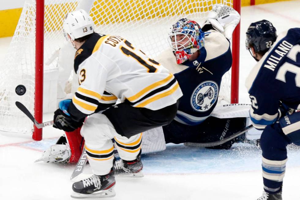 Columbus Blue Jackets goalie Elvis Merzlikins, center, of Latvia, stops a shot by Boston Bruins ...