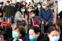 Passengers wearing protective face masks enter the departure hall of a high speed train station ...