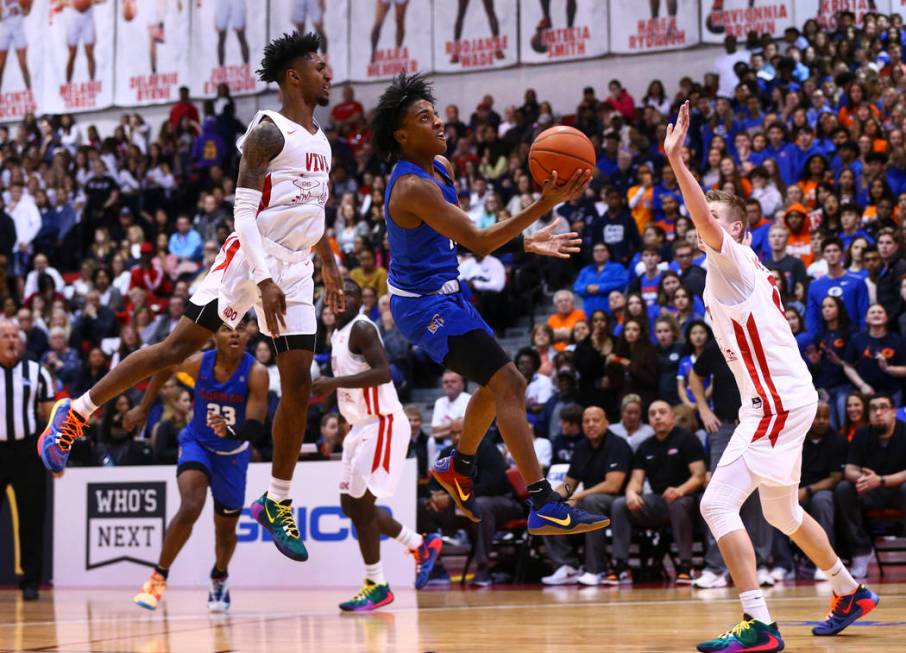 Bishop Gorman's Zaon Collins (10) goes to the basket between Coronado's Felix Reeves, left, and ...