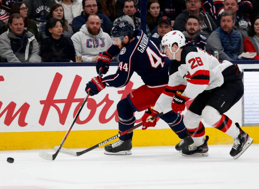 Columbus Blue Jackets defenseman Vladislav Gavrikov, left, of Russia, chases the puck in front ...