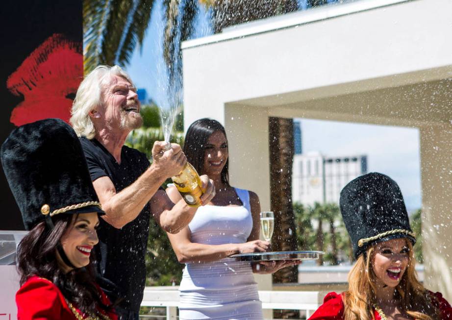 Virgin Group Founder Sir Richard Branson pops a champagne bottle following a press conference a ...