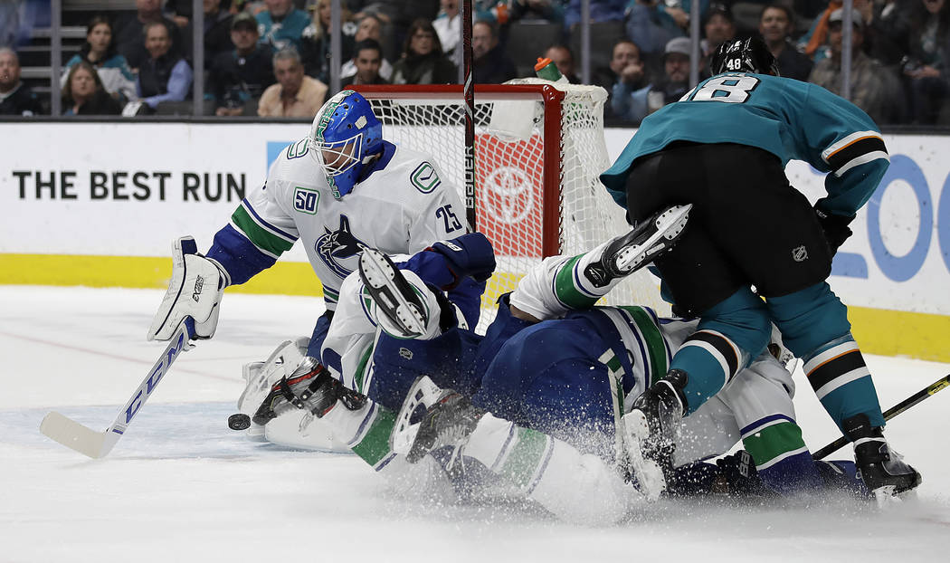 Vancouver Canucks goalie Jacob Markstrom, left, blocks a shot from San Jose Sharks' Tomas Hertl ...