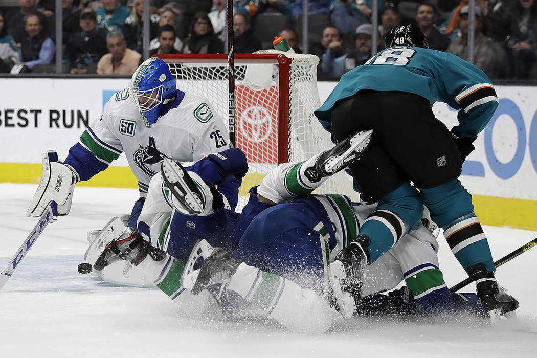 Vancouver Canucks goalie Jacob Markstrom, left, blocks a shot from San Jose Sharks' Tomas Hertl ...