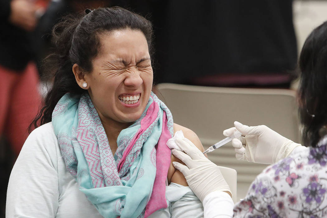 Ana Farfan reacts to getting an influenza vaccine shot at Eastfield College in Mesquite, Texas, ...